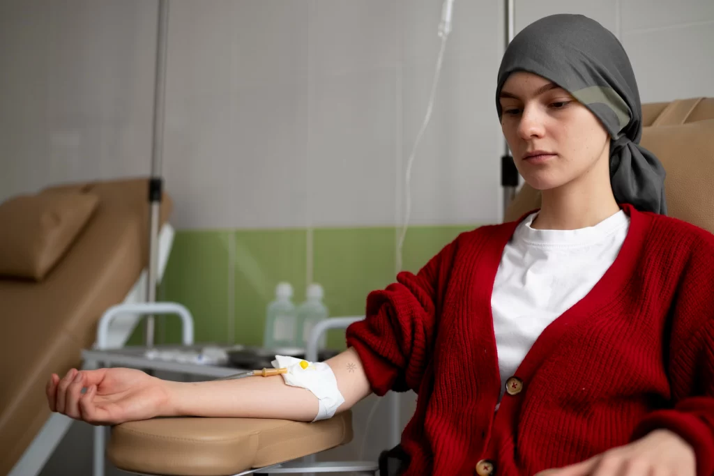 A woman undergoing chemotherapy sits in a treatment chair with an IV line in her arm, illustrating the reality behind common myths about chemotherapy.