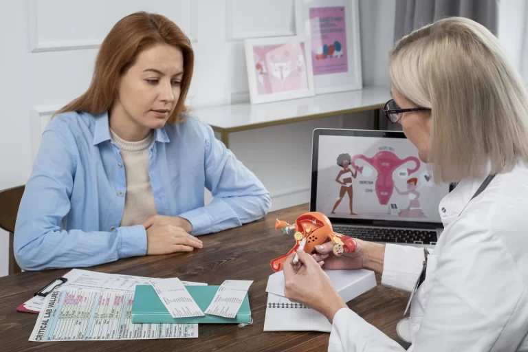 Gynecologist explaining ovarian health using a uterus model during a medical consultation with a female patient.